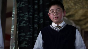 Movie still from “School of Rock” (2003), directed by Richard Linklater – A young man wearing glasses and a sweater vest; Medium shot, Low angle