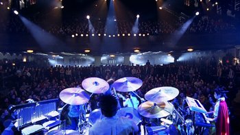 Movie still from “School of Rock” (2003), directed by Richard Linklater – A group of men playing drums in front of an audience; Extreme Wide shot, High angle