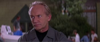 Movie still from “Scream 3” (2000), directed by Wes Craven – An older man in a black shirt and grey jacket; Close Up shot, Low angle