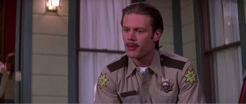 Movie still from “Scream 3” (2000), directed by Wes Craven – A man in a sheriff's uniform is looking at the camera; Close Up shot, Low angle