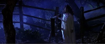 Movie still from “Scream 3” (2000), directed by Wes Craven – A woman in a white dress standing next to a wooden fence; Wide shot, Low angle