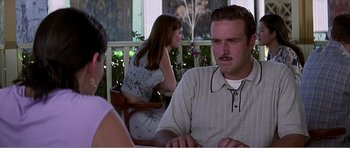 Movie still from “Scream 3” (2000), directed by Wes Craven – A man sitting at a table in front of two other people; Medium shot, Over the shoulder angle
