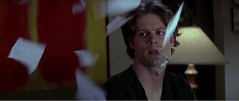 Movie still from “Scream 3” (2000), directed by Wes Craven – A man smoking a cigarette in front of papers; Close Up shot, Low angle