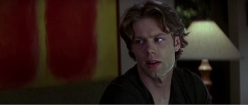 Movie still from “Scream 3” (2000), directed by Wes Craven – A young man with long brown hair stares at the camera; Close Up shot, Over the shoulder angle
