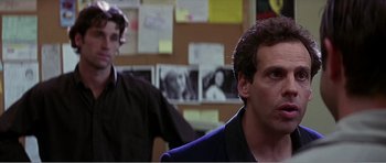 Movie still from “Scream 3” (2000), directed by Wes Craven – Two men are standing in front of a bulletin board; Close Up shot, Over the shoulder angle