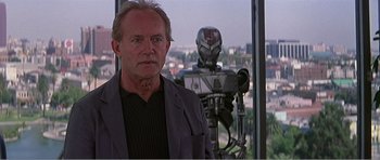 Movie still from “Scream 3” (2000), directed by Wes Craven – A man standing in front of a robot in front of a window; Medium shot, Over the shoulder angle