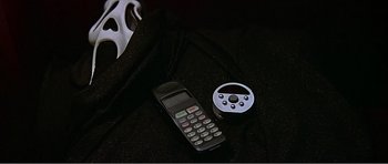 Movie still from “Scream 3” (2000), directed by Wes Craven – A cell phone next to a steering wheel on a table; Extreme Close Up shot, Overhead angle