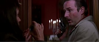 Movie still from “Scream 3” (2000), directed by Wes Craven – A man holding a gun in front of a mirror with candles; Close Up shot, Low angle