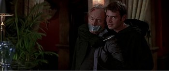 Movie still from “Scream 3” (2000), directed by Wes Craven – A man with his arm around another man with his mouth taped shut; Close Up shot, Over the shoulder angle