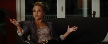 A woman sitting on top of a couch with her hand outstretched