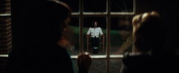 Movie still from “Scream 4” (2011), directed by Wes Craven – A man sitting in a chair in front of a window at night; Wide shot, Over the shoulder angle