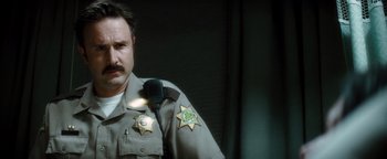 Movie still from “Scream 4” (2011), directed by Wes Craven – A man in a sheriff's uniform is looking at the camera; Close Up shot, Low angle