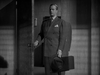 Movie still from “Secret Beyond the Door...” (1947), directed by Fritz Lang – A black and white photo of a man in a suit and tie; Medium shot, Low angle