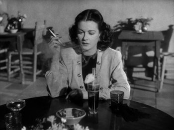 Movie still from “Secret Beyond the Door...” (1947), directed by Fritz Lang – A woman sitting at a table with a glass of soda; Medium shot, High angle
