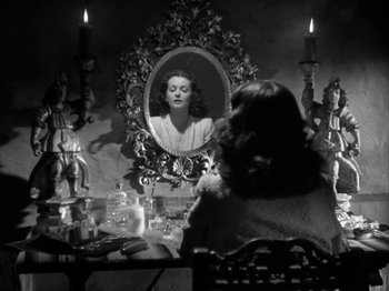Movie still from “Secret Beyond the Door...” (1947), directed by Fritz Lang – A woman sitting in front of a mirror in front of candles; Medium shot, Over the shoulder angle