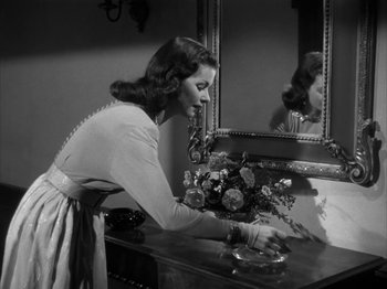 Movie still from “Secret Beyond the Door...” (1947), directed by Fritz Lang – A black - and - white photo of a woman arranging flowers; Medium shot, Low angle