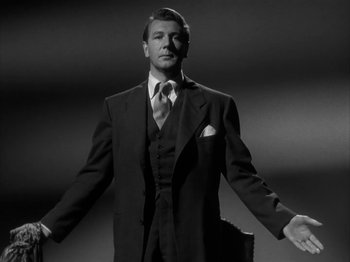 Movie still from “Secret Beyond the Door...” (1947), directed by Fritz Lang – A black and white photo of a man in a suit and tie; Medium shot, Low angle