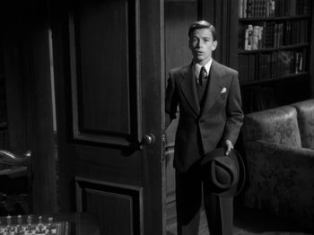Movie still from “Secret Beyond the Door...” (1947), directed by Fritz Lang – A man in a suit and hat standing in front of an open door; Medium shot, High angle