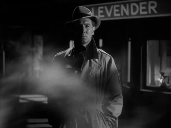 Movie still from “Secret Beyond the Door...” (1947), directed by Fritz Lang – A black and white photo of a man in a trench coat and a hat; Medium shot, Low angle