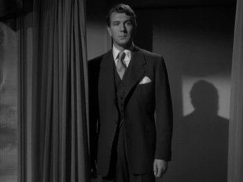 Movie still from “Secret Beyond the Door...” (1947), directed by Fritz Lang – A black and white photo of a man in a suit and tie; Medium shot, Low angle