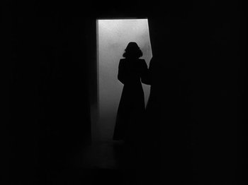 Movie still from “Secret Beyond the Door...” (1947), directed by Fritz Lang – A woman standing in front of an open door in a dark room; Wide shot, Low angle