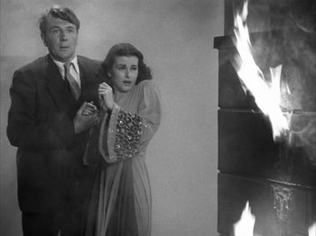 Movie still from “Secret Beyond the Door...” (1947), directed by Fritz Lang – A man and a woman standing in front of a fire; Medium shot, Low angle