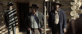 Movie still from “Godless” (2017), directed by Scott Frank – Two men standing next to each other in front of a log cabin; Medium shot, Low angle
