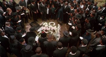 Movie still from “Secrets & Lies” (1996), directed by Mike Leigh – A group of people gathered around a grave with flowers; Wide shot, High angle