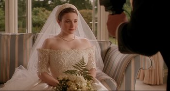 Movie still from “Secrets & Lies” (1996), directed by Mike Leigh – A woman in a wedding dress sitting on a couch; Medium shot, Over the shoulder angle