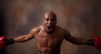 Movie still from “Secrets & Lies” (1996), directed by Mike Leigh – A man with a bare chest is screaming with his mouth wide open; Medium shot, Low angle