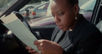 Movie still from “Secrets & Lies” (1996), directed by Mike Leigh – A person sitting in a car looking at a paper; Close Up shot, High angle