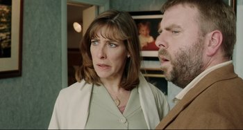 Movie still from “Secrets & Lies” (1996), directed by Mike Leigh – A woman standing next to a man in a room; Medium shot, Over the shoulder angle