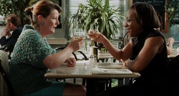 Movie still from “Secrets & Lies” (1996), directed by Mike Leigh – Two women sitting at a table holding wine glasses; Medium shot, High angle