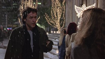 Movie still from “Serendipity” (2001), directed by Peter Chelsom – A man standing in the snow near a group of people; Medium shot, Over the shoulder angle