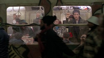 Movie still from “Serendipity” (2001), directed by Peter Chelsom – A man riding on a subway train with people looking out the window; Wide shot, Over the shoulder angle