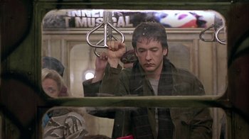 Movie still from “Serendipity” (2001), directed by Peter Chelsom – A man holding a metal object in his hand; Medium shot, Low angle