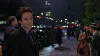 Movie still from “Serendipity” (2001), directed by Peter Chelsom – A man in a suit standing in the middle of a street; Close Up shot, Over the shoulder angle