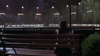 Movie still from “Serendipity” (2001), directed by Peter Chelsom – A woman sitting on a bench looking out a window at night; Wide shot, High angle