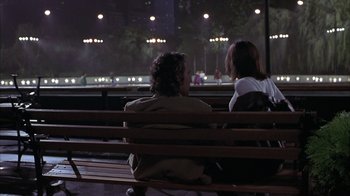 Movie still from “Serendipity” (2001), directed by Peter Chelsom – Two people sitting on a wooden bench at night; Medium shot, Over the shoulder angle