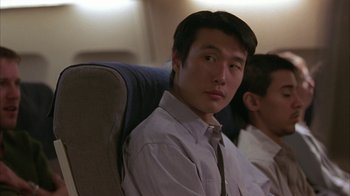 Movie still from “Serendipity” (2001), directed by Peter Chelsom – A man sitting on a seat on an airplane; Close Up shot, Over the shoulder angle