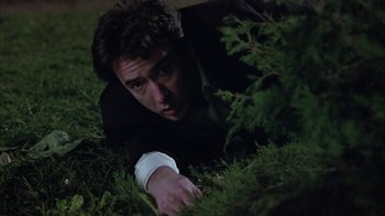 Movie still from “Serendipity” (2001), directed by Peter Chelsom – A man laying in the grass looking at the camera; Medium shot, Low angle