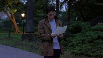 Movie still from “Serendipity” (2001), directed by Peter Chelsom – A man standing on the side of a road reading a piece of paper; Medium shot, Over the shoulder angle