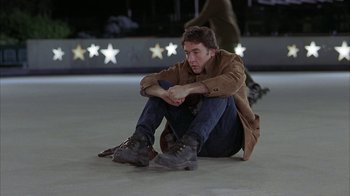 Movie still from “Serendipity” (2001), directed by Peter Chelsom – A man sitting on the ground with his hands on his knees; Medium shot, High angle