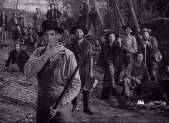 Movie still from “Sergeant York” (1941), directed by Howard Hawks – A group of people in a field with a man holding a rifle; Medium shot, Low angle
