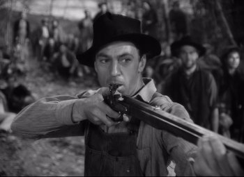 Movie still from “Sergeant York” (1941), directed by Howard Hawks – An old photo of a man holding a gun; Medium shot, Over the shoulder angle