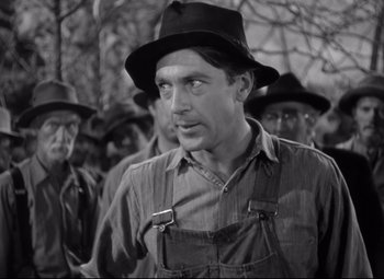 Movie still from “Sergeant York” (1941), directed by Howard Hawks – A man wearing a hat standing in front of a group of men; Medium shot, Over the shoulder angle