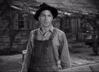 Movie still from “Sergeant York” (1941), directed by Howard Hawks – A man wearing a hat and overalls standing in front of a building; Close Up shot, Over the shoulder angle