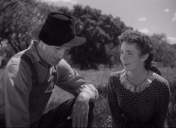 Movie still from “Sergeant York” (1941), directed by Howard Hawks – A man and a woman sitting in a grassy field; Medium shot, Over the shoulder angle