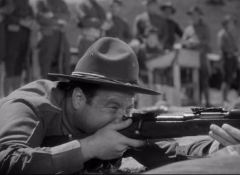 Movie still from “Sergeant York” (1941), directed by Howard Hawks – An old photo of a man with a gun; Medium shot, Over the shoulder angle