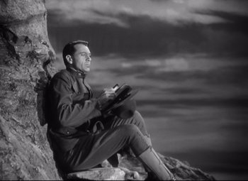 Movie still from “Sergeant York” (1941), directed by Howard Hawks – A black and white photo of a man sitting on a rock; Medium shot, Low angle